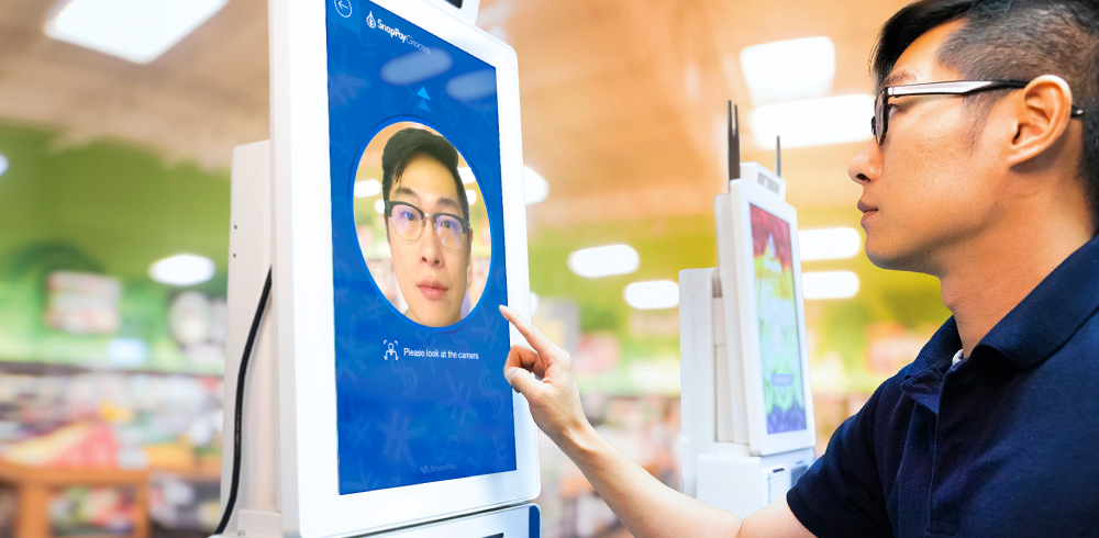 a young man touching a large screen with his face on it